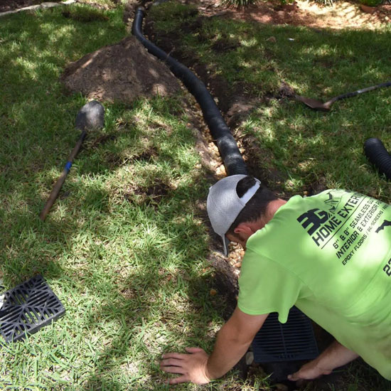 A man kneeling down in the grass next to an electric pole.