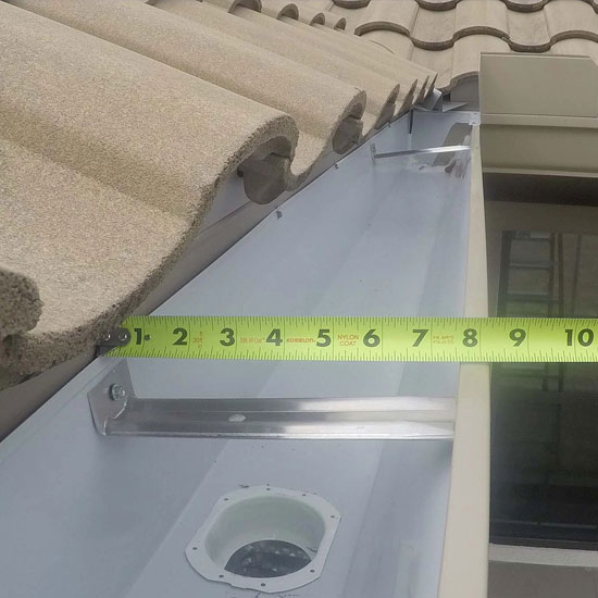A tape measure is measuring the length of a roof.