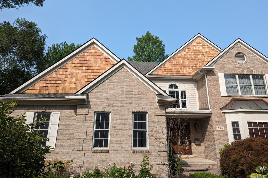 A brick house with wood shingles and a white door.