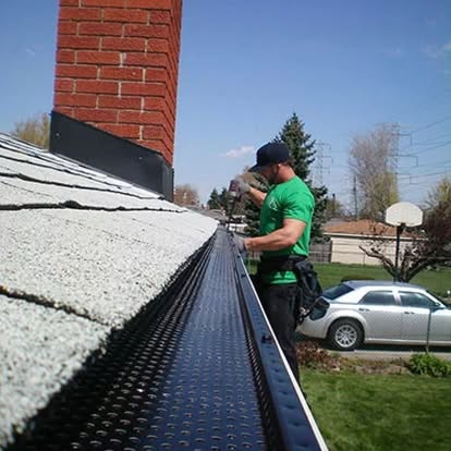 A man is working on the gutter of his home.