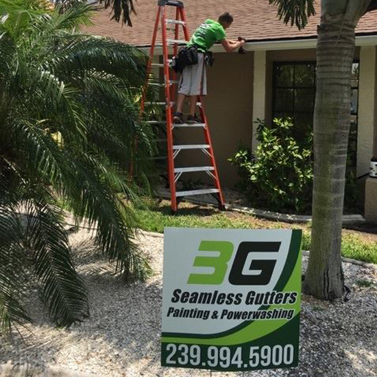 A man on a ladder painting the side of a house.