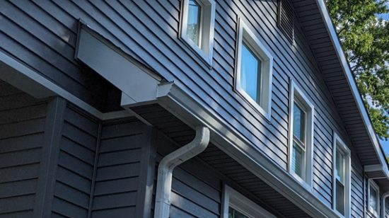 A close up of the side of a house with windows and a gutter.