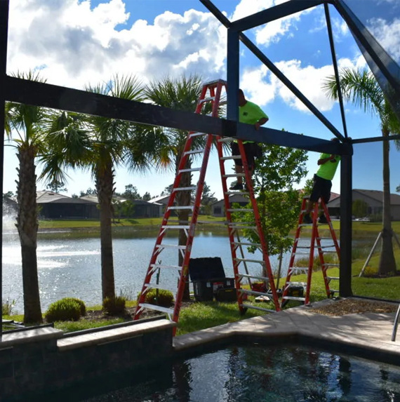 A man on a ladder next to a pool.