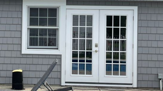 A white door with two windows and a pool in the background.